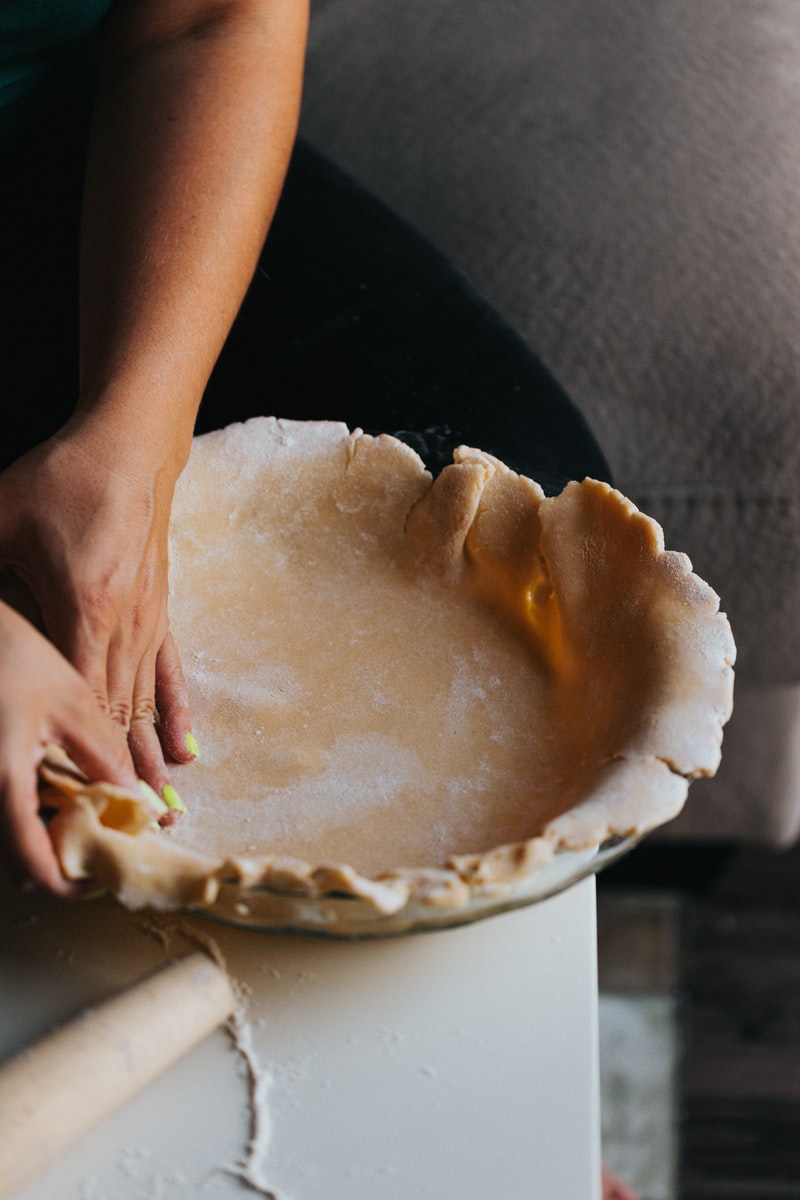 person holding white ceramic bowl with brown and white cake